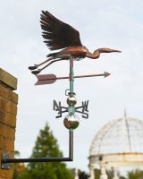 The Soaring Heron Verdigris Copper Weathervane Shown Mounted onto a Red Brick Wall in a Garden