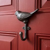 The Songbird Single Cast Iron Coat Hook Shown on a Red Door up Close - Digital Illustration