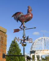 The Striding Rooster Verdigris Copper Weathervane Shown Mounted on a Brick Wall in a Garden