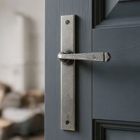 The Tapered Slimline Lever Espagnolette Door Latch in Pewter Shown on a Dark Grey Door in a Modern Home Interior - Digital Illustration
