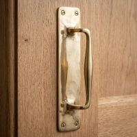 The Taproom Integral Plate Polished Brass Door Pull - 300mm Mounted on a Wooden Door - Digital Illustration