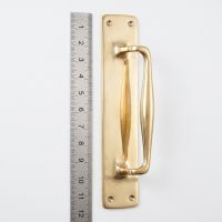 The Taproom Integral Plate Polished Brass Door Pull - 300mm on a White Background next to a Steel Ruler for Scale - Digital Illustration