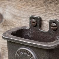The Tavern "Enjoy Your Drink" Cast Iron Bottle Cap Catcher Showing a Close up of the Wall attachement