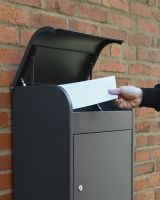 The "Titan" Medium Wall Mounted Parcel Box Steel in Grey Showing a parcel being Deposited inside