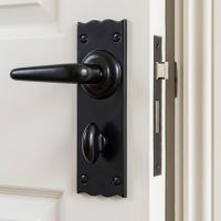 The Traditional Black Bathroom Mortice Lock Door Handle Set Shown Mounted on a White Bathroom Door - Digital Illustration
