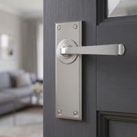 The Valen Lever Latch Door Handle Set in Satin Stainless Steel Shown on an Open Door Leading to a Living Room - Digital Illustration