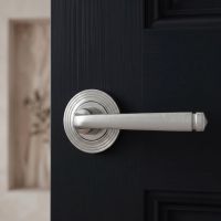 The Valen Tapered Sprung Handle Set on a Long Backplate in Satin Stainless Steel in a Modern Interior Setting on a Contrasting Black Door - Digital Illustration