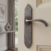 The Verona Curved Pewter Medieval Lever Handle Shown Mounted on a Cream Door in a Traditional Home - Digital Illustration