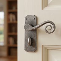 The Vervet Pewter Monkey tail Lever Bathroom Set Shown Close up on a Classic Cream Coloured Door - Digital Illustration