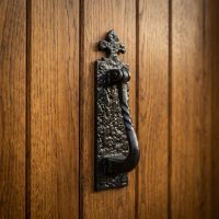 The Wellcroft Cast Iron Fleur de Lys Door Knocker on a Traditional Timber Foor Shown Close up - Digital Illustration