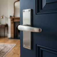 The 115mm Victorian Straight Door Lever Handles in Satin Chrome Shown on the Door to a Cosy Living room - Digital Illustration