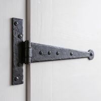 The 12" Round Ended Beeswax Tee Hinges Displayed on a White Open Door - Digital Illustration