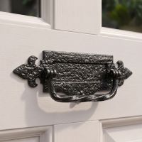 The 12 Inch Traditional Black Iron Fleur-De-Lys Letter Plate With Integral Knocker Mounted on a White Door Front Entrance - Digital Illustration