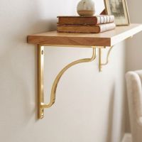 The 150mm x 150mm Polished Brass "Arch-Way" Modern Shelf Bracket Use as a DIY Shelf on a Cream Coloured Wall - Digital Illustration The 150mm x 150mm Polished Brass "Arch-Way" Modern Shelf Bracket Use as a DIY Shelf on a Cream Coloured Wall - Digital Illustration