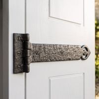 The 18 Inch Antique Black Malleable Iron Door Hinge With Heavy Strap (Pair) on the A White Door Inside a Country Home - Digital Illustration