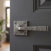 The "Airedale" Sprung Pewter Iron Door Handle Set on a Dark Grey Door in a Modern Home Hallway - Digital Illustration