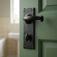 The "Aldrington" Cottage Lever Bathroom Set on a Green Bathroom Door with a Sink in the Background - Digital Illustration