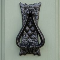 The "Alfarr" Bedroom Door Knocker Shown From the Front Mounted on a Light Green Door - Digital Illustration