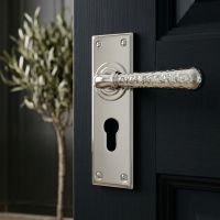 The "Amsden House" Hammered Polished Nickel Lever Euro Door Handle on a Sleek Black Door in a Modern Hallway - Digital Illustration