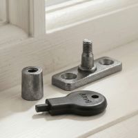 The "Bolsover" Pewter Locking Stay Pin Placed in Front of a Wooden White Window Frame in a Modern Home - Digital Illustration 