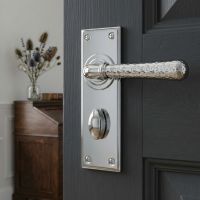 The "Harriot House" Hammered Bright Chrome Lever Bathroom Door Handle on a Charcoal Grey Door in a Modern Home Interior - Digital Illustration 