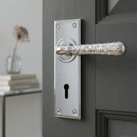 The "Harriot House" Hammered Bright Chrome Lever Lock Door Handle on a Charcoal Grey Door in a Cosy Home Interior - Digital Illustration