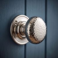 The "Morton Manor" Polished Nickel Hammered Mortice & Rim Doorknob Set on a Dark Blue Panelled Door - Digital Illustration 