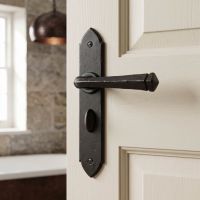 The "Orelia" Beeswax Square Iron Gothic Lever Handles and Bathroom Lock Shown on a White Door to a Modern Ensuite - Digital Illustration
