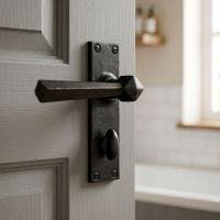 The "Peregrine" Beeswax Straight Lever Bathroom Set on a Grey Bathroom Door Shown in the Daytime - Digital Illustration The "Peregrine" Beeswax Straight Lever Bathroom Set on a Grey Bathroom Door Shown in the Daytime - Digital Illustration