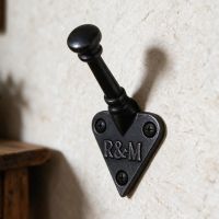 The "R&M" Iron Coat Hook on a Cream Coloured Wall in a Well Lit Hall - Digital Illustration