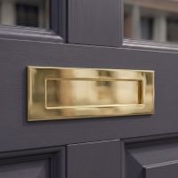 The "Sandhill" Cast Brass Letter Plate in a Brass Finish on a Dark Grey Coloured Front Door with Glass Panels - Digital Illustration 