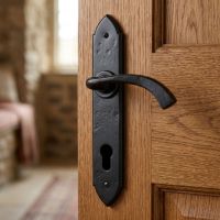 The "Verona" Black Gothic Curved Espagnolette Lock Set mounted on the Door of a Rustic Cottage Living Room - Digital Illustration