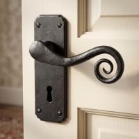 The "Ververt" Beeswax Monkeytail Lever Handle Set with Key Hole Shown Close up on a Door in a Traditional Home - Digital Illustration 