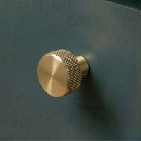 The 25mm "Vesper" Knurled Edge Cabinet Knob in Aged Brass Designed for Kitchen Cupboards Mounted on a Blue Drawer - Digital Illustration 