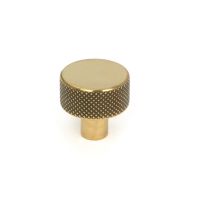 The 25mm "Vesper" Knurled Edge Cabinet Knob in Aged Brass on a White Background Stood Upright