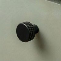 The 25mm "Vesper" Knurled Edge Cabinet Knob in Matt Black for Kitchen Cupboards Mounted on a Sage Green Drawer - Digital Illustration 
