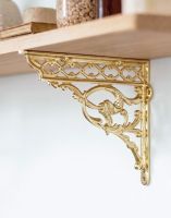 The 29 x 33cm Brass Serpent Design Shelf Bracket Being Used to Support a Wooden DIY Shelf on a White Interior Wall - Digital Illustration The 29 x 33cm Brass Serpent Design Shelf Bracket Being Used to Support a Wooden DIY Shelf on a White Interior Wall - Digital Illustration