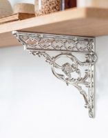 The 29cm x 33cm Serpent Design Chrome Wall Bracket Attached to a Wooden DIY Shelf on a White Coloured Wall - Digital Illustration 