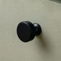 The 32mm "Atelier" Circular Cabinet Knob in Matt Black Designed for Kitchen Cupboards on a Sage Green Cupboard - Digital Illustration