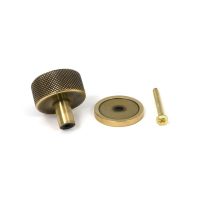 The 32mm Knurled Cabinet Knob on Plain Rose in Aged Brass Shown with Fitting Bolt on a White Background The 32mm Knurled Cabinet Knob on Plain Rose in Aged Brass Shown with Fitting Bolt on a White Background