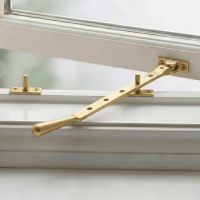 The 335mm 12" Satin Brass Five Pin Window Stay on a White Window Frame in a Country Home - Digital Illustration The 335mm 12" Satin Brass Five Pin Window Stay on a White Window Frame in a Country Home - Digital Illustration