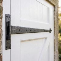 The 35" External Beeswax Hook & Band Tee Hinge Mounted on a White Garage Side Door in a Garden - Digital Illustration 