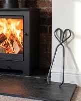 The 37cm Black Iron Fireplace Log Tongs  on a Stone Tiled Floor Next to a Log Basket - Digital Illustration