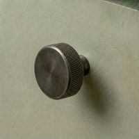 The 38mm "Vesper" Knurled Edge Cabinet Knob in Pewter Designed for Kitchen Cupboards and Displayed on a Green Drawer - Digital Illustration 