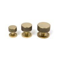 The 38mm Knurled Cabinet Knob on a Plain Rose in Aged Brass Next to Other Available Sizes on a White Background The 38mm Knurled Cabinet Knob on a Plain Rose in Aged Brass Next to Other Available Sizes on a White Background