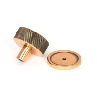 The 38mm Knurled Cabinet Knob on a Plain Rose in Polished Bronze Shown from Behind on a White Background