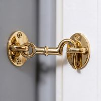The 3 Inch Brass Cabin Hooks Loose Ring Type in a Well lit Living Space on a White Door - Digital Illustration 