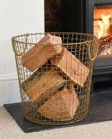 The 41cm Brass Plated Wire Log Basket adjacent to Lit Log Burner Stove in a Modern Home - Digital Illustration  