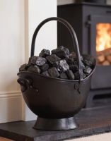 The 53cm "Waterloo" Black Iron Coal Bucket Placed in a Contemporary Living Room with a Log Burner Behind - Digital Illustration 
