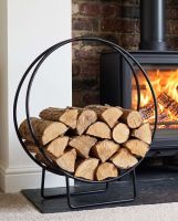 The 69.5cm Black Contemporary Circular Log Rack & Holder With Brown Handle next to a lit Traditional Log Burner - Digital Illustration The 69.5cm Black Contemporary Circular Log Rack & Holder With Brown Handle next to a lit Traditional Log Burner - Digital Illustration